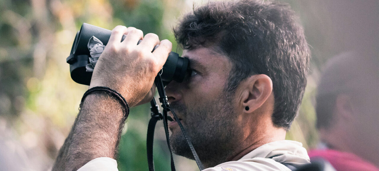 A birder viewing birds with a binocular